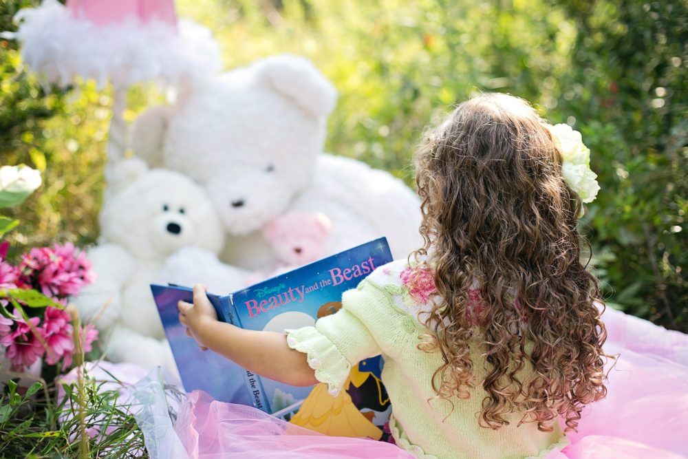 little girl reading to her toys